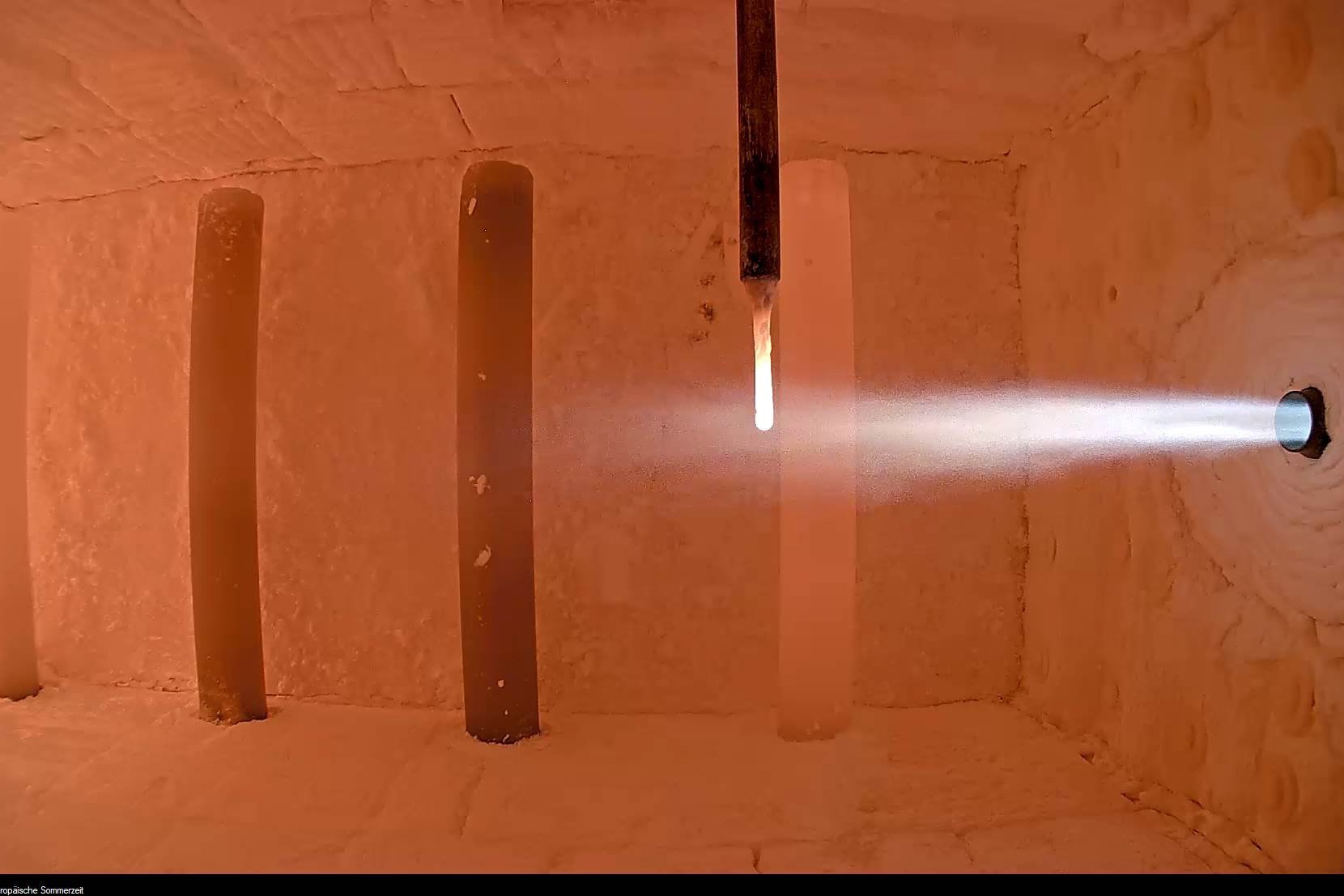 Das Bild zeigt eine Brennkammer mit laufendem Versuchsaufbau, in dem ein Ammoniakbrenner in Betrieb ist. Der Brennerstrahl tritt in die aufgeheizte Kammer ein und verdeutlicht die experimentelle Nutzung von Ammoniak (NH₃) als CO₂-freien Brennstoff. Diese Aufnahme steht für die Forschungsaktivitäten des GWI zur Dekarbonisierung energieintensiver Industrieprozesse mithilfe innovativer Brennstoffe.