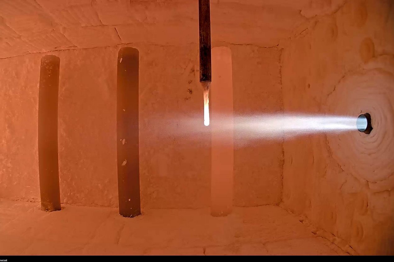 Das Bild zeigt eine Brennkammer mit laufendem Versuchsaufbau, in dem ein Ammoniakbrenner in Betrieb ist. Der Brennerstrahl tritt in die aufgeheizte Kammer ein und verdeutlicht die experimentelle Nutzung von Ammoniak (NH₃) als CO₂-freien Brennstoff. Diese Aufnahme steht für die Forschungsaktivitäten des GWI zur Dekarbonisierung energieintensiver Industrieprozesse mithilfe innovativer Brennstoffe.