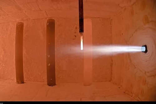 Das Bild zeigt eine Brennkammer mit laufendem Versuchsaufbau, in dem ein Ammoniakbrenner in Betrieb ist. Der Brennerstrahl tritt in die aufgeheizte Kammer ein und verdeutlicht die experimentelle Nutzung von Ammoniak (NH₃) als CO₂-freien Brennstoff. Diese Aufnahme steht für die Forschungsaktivitäten des GWI zur Dekarbonisierung energieintensiver Industrieprozesse mithilfe innovativer Brennstoffe.