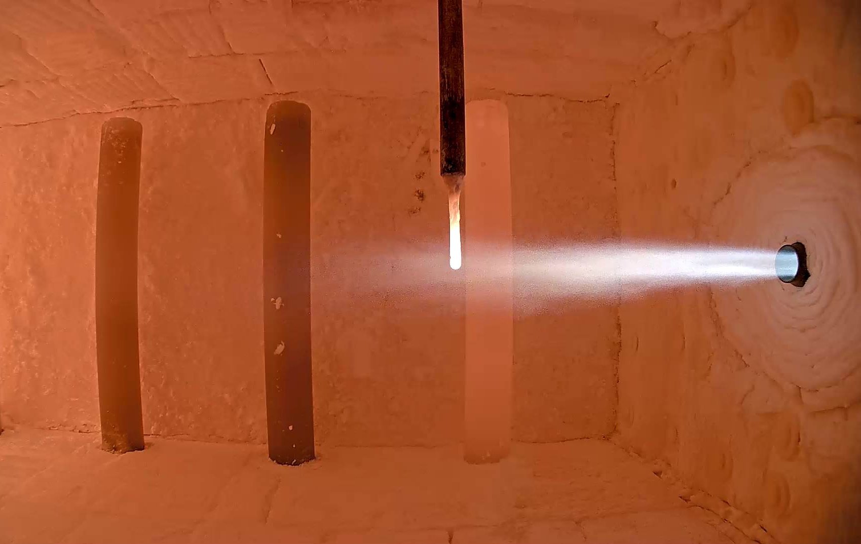 Das Bild zeigt eine Brennkammer mit laufendem Versuchsaufbau, in dem ein Ammoniakbrenner in Betrieb ist. Der Brennerstrahl tritt in die aufgeheizte Kammer ein und verdeutlicht die experimentelle Nutzung von Ammoniak (NH₃) als CO₂-freien Brennstoff. Diese Aufnahme steht für die Forschungsaktivitäten des GWI zur Dekarbonisierung energieintensiver Industrieprozesse mithilfe innovativer Brennstoffe.