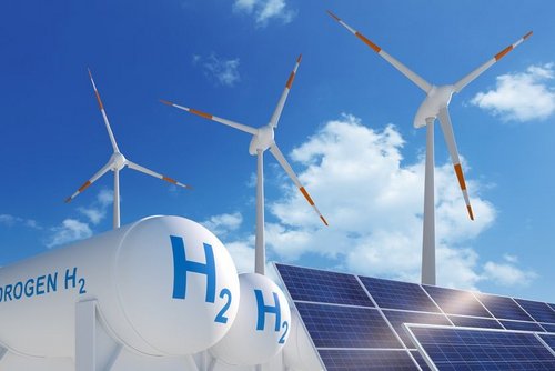 Das Bild zeigt große Wasserstofftanks (H₂) im Vordergrund, flankiert von Windkraftanlagen und einem Solarmodul. Diese Komposition symbolisiert die Verknüpfung erneuerbarer Energien mit der Wasserstofftechnologie und verdeutlicht deren zentrale Rolle in der Energiewende.
